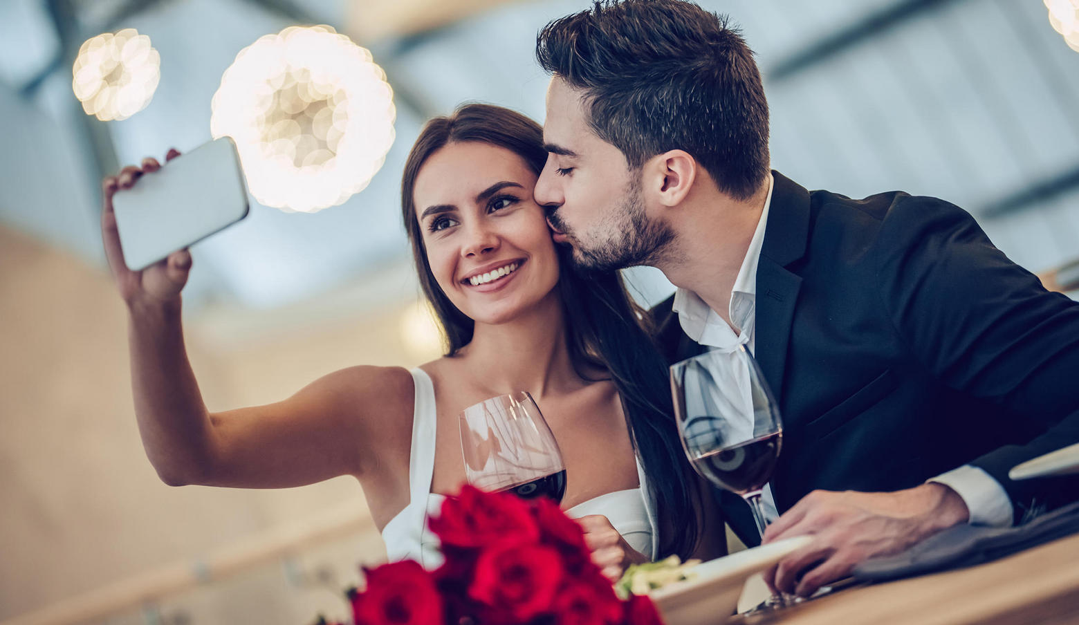 couple taking selfie with wine and roses
