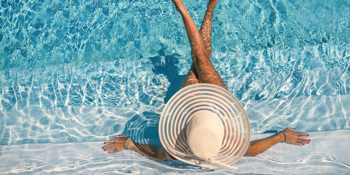Woman with hat sitting in pool